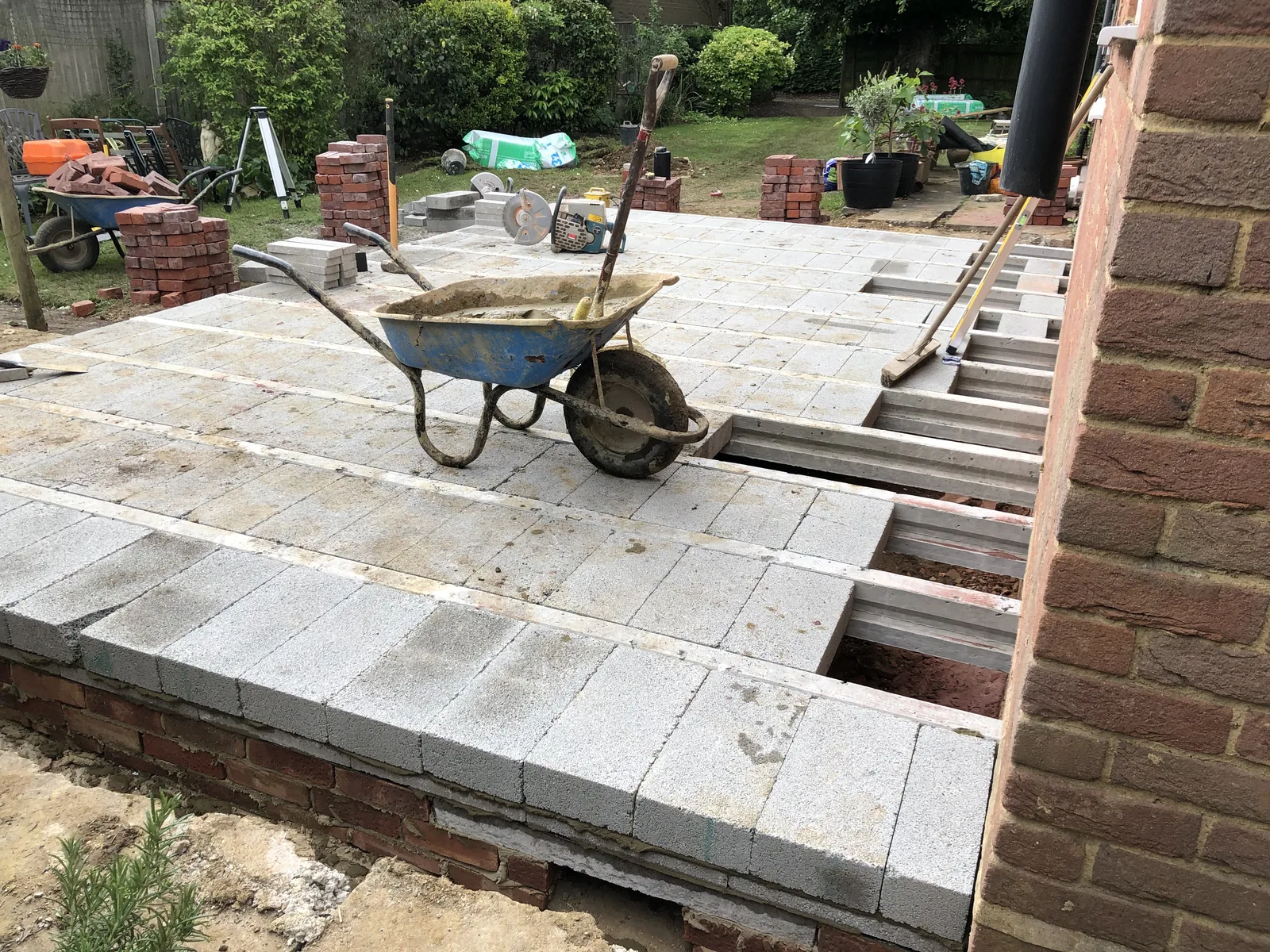 A suspended beam-and-block ground floor part-laid over the new brick foundation walls, with concrete blocks dropped between the beams and a gap still open at one end.