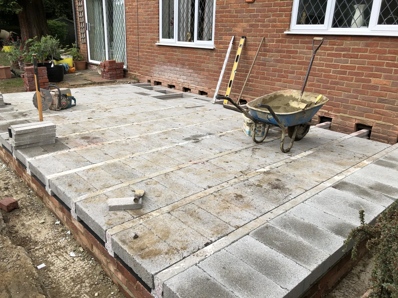 The completed beam-and-block floor deck from the garden side, laid dead level across the brickwork and butted up against the existing rear wall of the house.