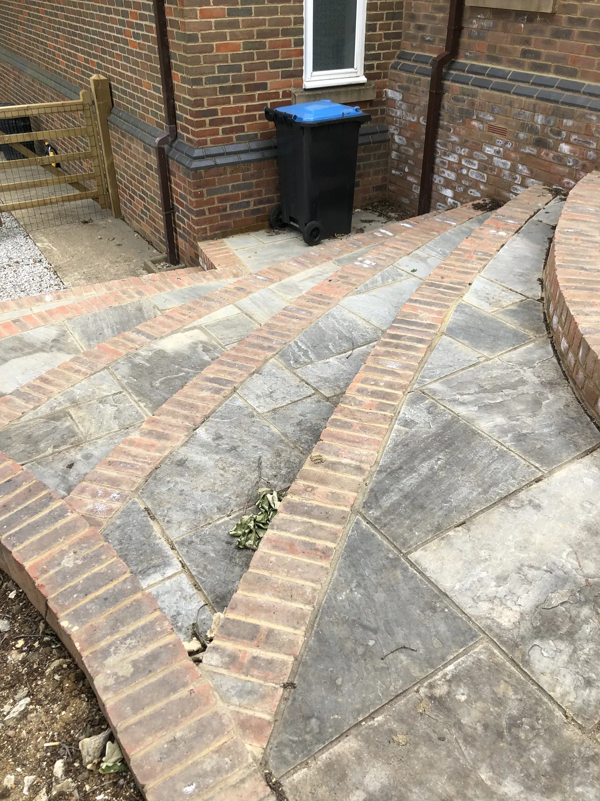 Bands of brick fanned out through the stone paving to turn the corner of the house, with the curved brick edging carried on around the terrace beyond.
